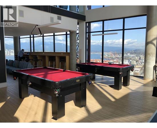 A man is working on a pool table in a room with large windows.