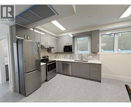A modern kitchen with stainless steel appliances and marble flooring.