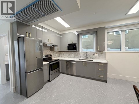 A modern kitchen with stainless steel appliances and marble flooring.