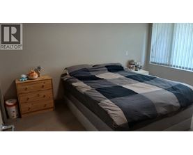 A bedroom with a bed, nightstand, and a drawer.