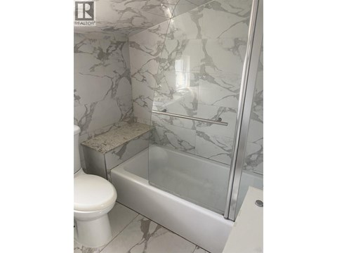 A white toilet sits next to a marble tiled shower.