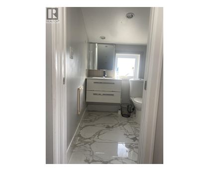 A bathroom with a marble floor and white walls.