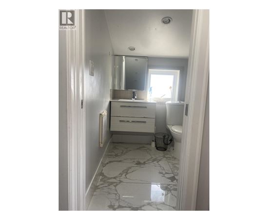 A bathroom with a marble floor and white walls.