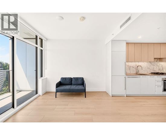 A living room with a blue couch and a kitchen area in the background.