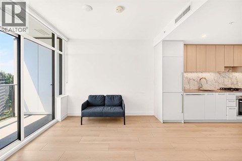 A living room with a blue couch and a kitchen area in the background.