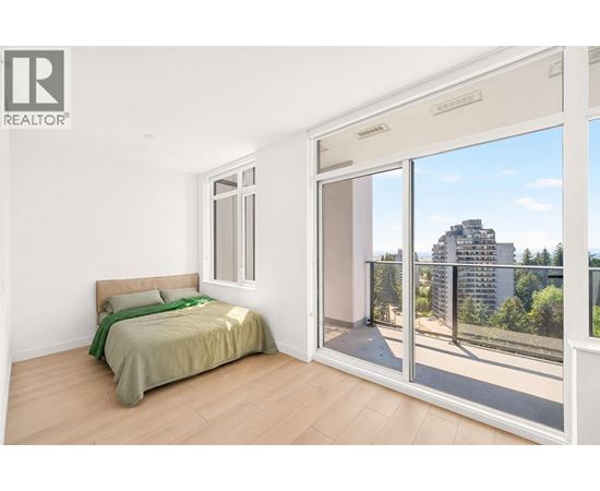 A bedroom with a bed, a window, and a sliding glass door leading to a balcony.