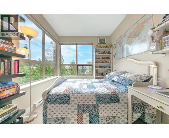 A bedroom with a bed, desk, and bookshelf.