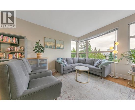 A living room with grey couches, a coffee table, and a bookshelf.