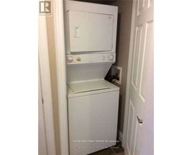 A white dishwasher and dryer are stacked in a small space.