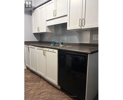 A kitchen with white cabinets and a black dishwasher.