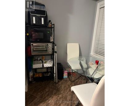 A room with a microwave on top of a shelf and a glass table with a white chair.