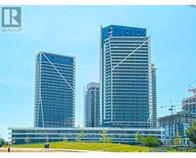 A tall building with a glass facade stands in front of a smaller building.