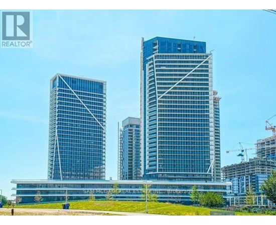 A tall building with a glass facade stands in front of a smaller building.