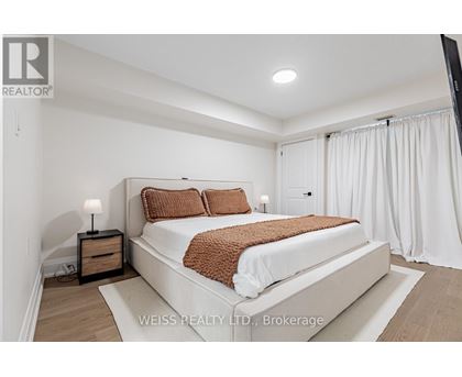 A bedroom with a large bed and a nightstand with a lamp.