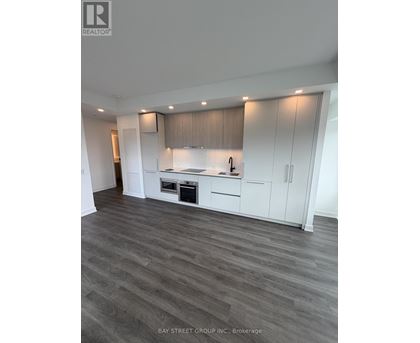 A spacious kitchen with white cabinets and a wooden floor.