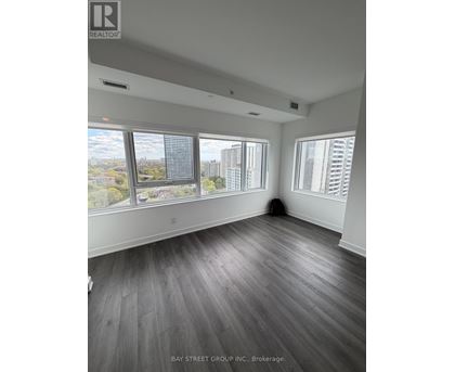A spacious room with a view of the cityscape through large windows.