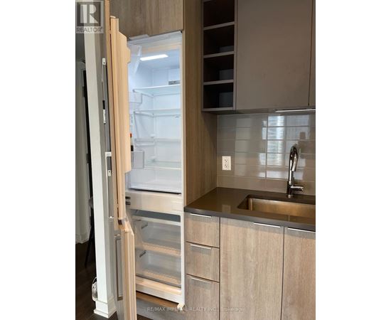 A kitchen with a refrigerator and a sink.