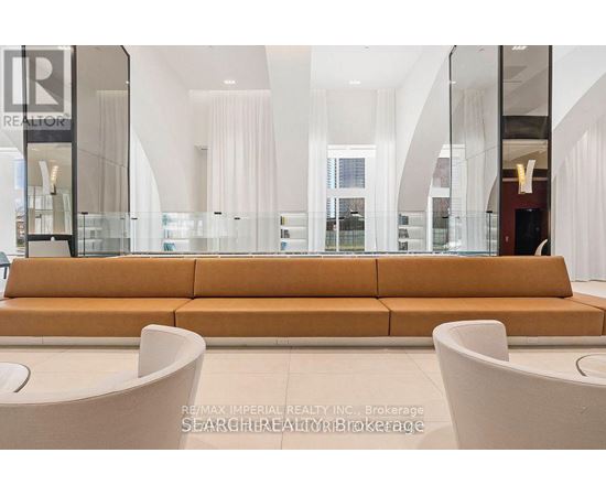 A large, modern living room with a long sofa and a glass display case.