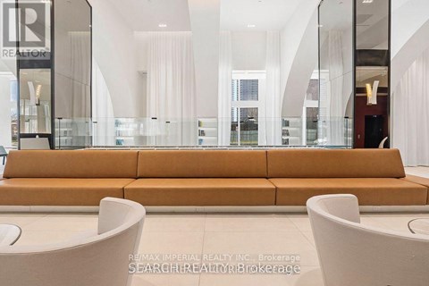 A large, modern living room with a long sofa and a glass display case.