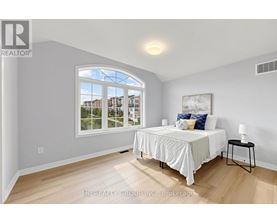 A bedroom with a large bed and a window overlooking a residential area.