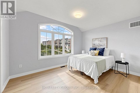 A bedroom with a large bed and a window overlooking a residential area.