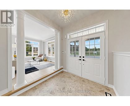 A spacious room with a chandelier, a door, and a view of the outside.