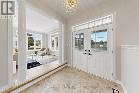 A spacious room with a chandelier, a door, and a view of the outside.