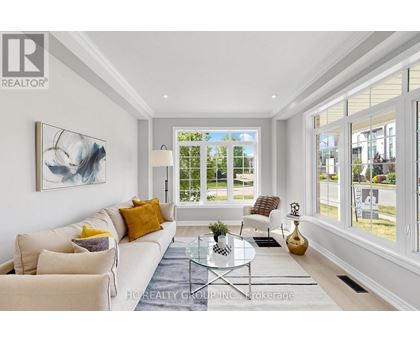 A well-lit living room with a white sofa, a glass coffee table, and a large painting on the wall.