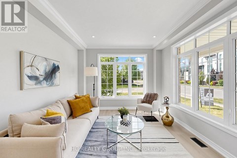 A well-lit living room with a white sofa, a glass coffee table, and a large painting on the wall.