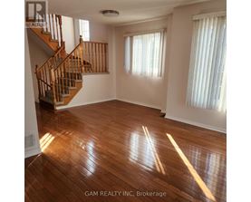 A well-lit, spacious room with a staircase leading to the upper floor.