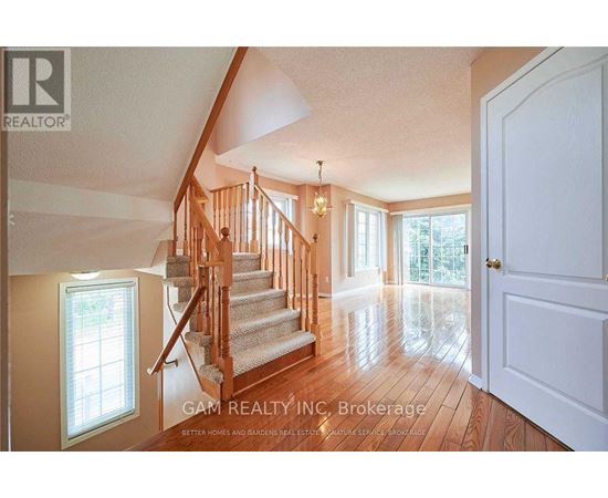 A well-lit, spacious room with a staircase leading to the upper floor.