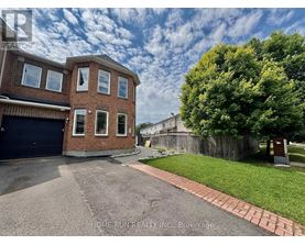 A brick house with a garage and a tree in front.