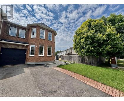 A brick house with a garage and a tree in front.