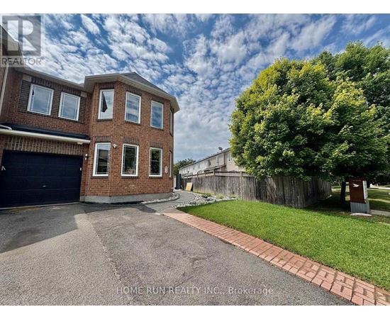 A brick house with a garage and a tree in front.