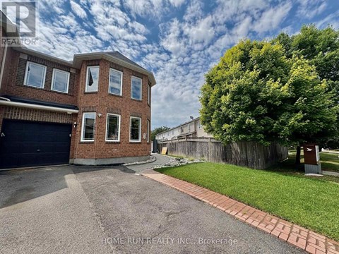 A brick house with a garage and a tree in front.