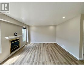A spacious room with a fireplace and wood flooring.
