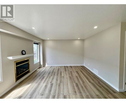 A spacious room with a fireplace and wood flooring.