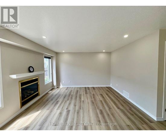 A spacious room with a fireplace and wood flooring.