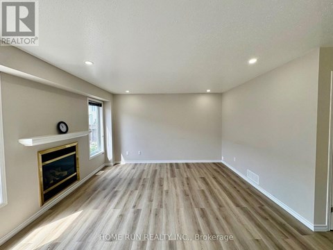 A spacious room with a fireplace and wood flooring.