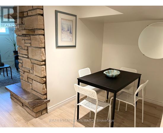 A dining room with a stone fireplace and a table set with chairs.