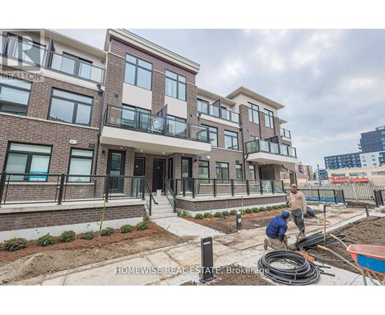 A construction site for a multi-story residential building with workers installing exterior elements.