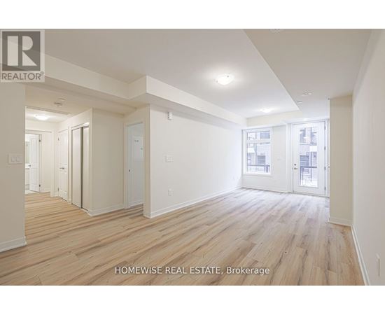 A spacious room with wooden flooring and white walls.