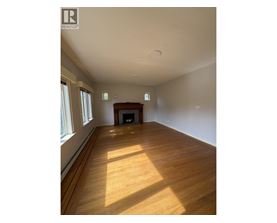 A large empty room with wooden floors and a fireplace.