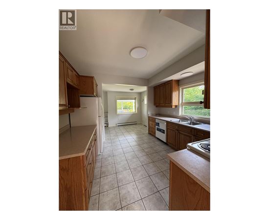 A kitchen with wooden cabinets and a tiled floor.
