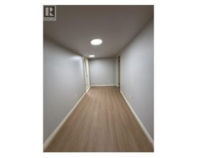 A long hallway with wood floors and white walls.
