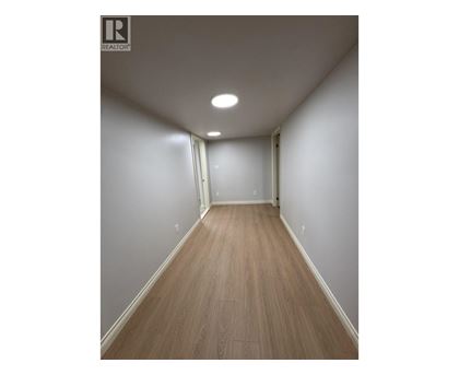 A long hallway with wood floors and white walls.