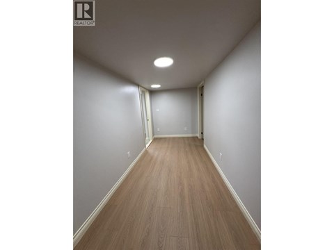 A long hallway with wood floors and white walls.