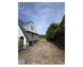A house with a grey roof and a dirt path leading to it.