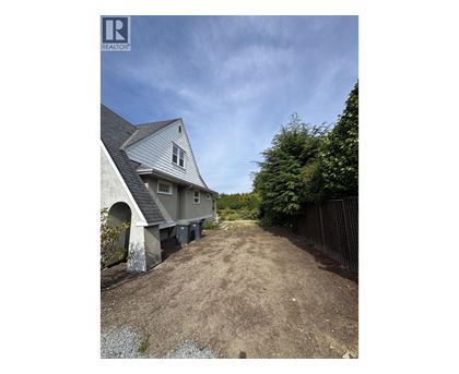 A house with a grey roof and a dirt path leading to it.