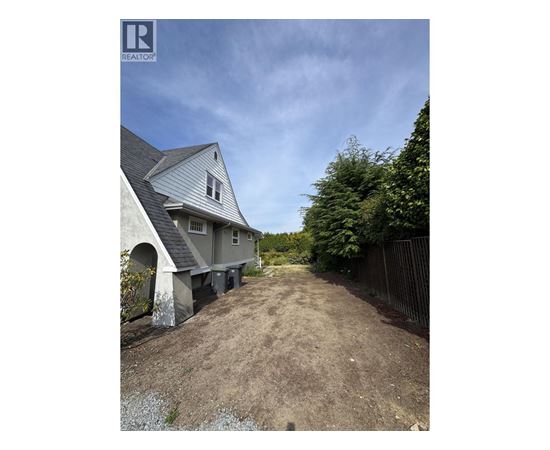 A house with a grey roof and a dirt path leading to it.